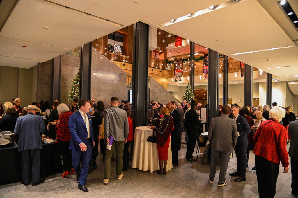 Group of well-dressed people in the lobby of the DSO eating catering from Blue Star Detroit.